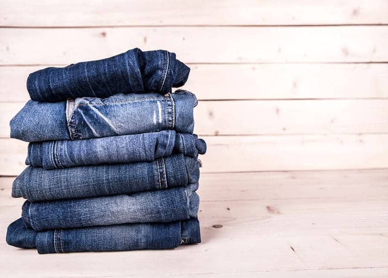 Six pairs fashionably faded blue denim jeans neatly stacked