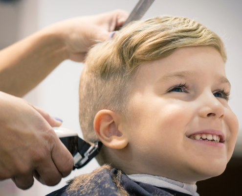 Blond little boy having a haircut at hair salon