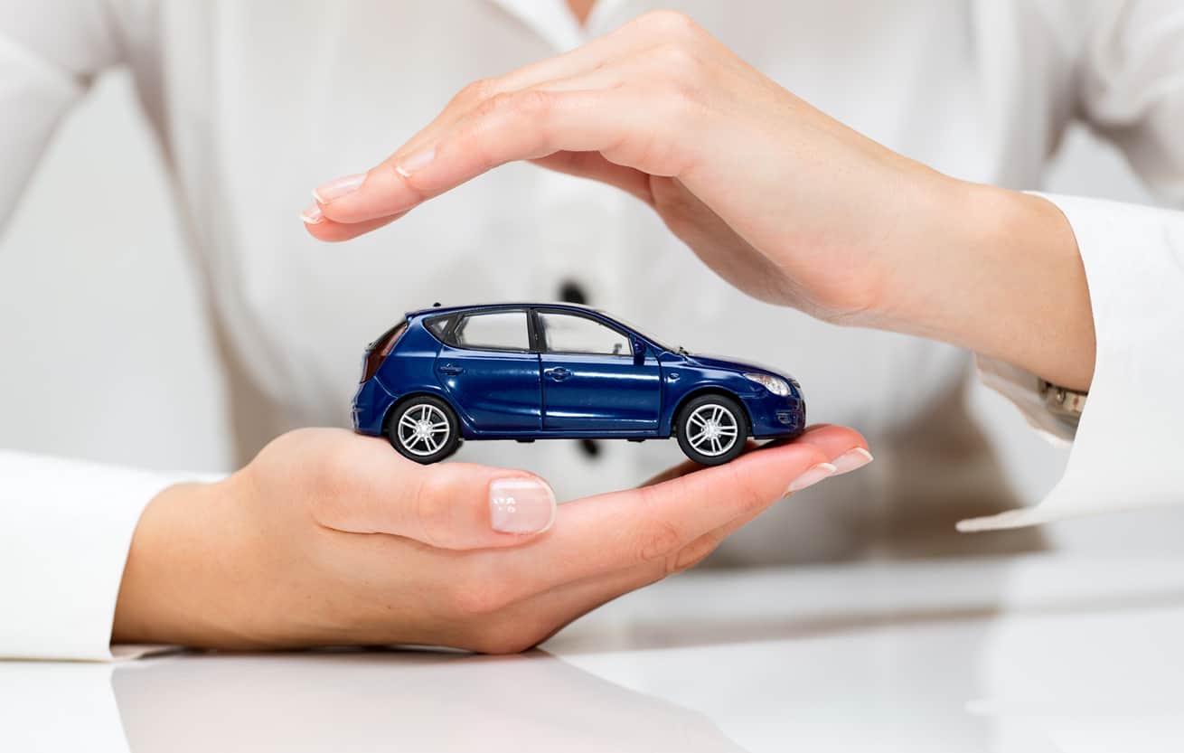 female hands holding toy care to represent protection with cheap car insurance