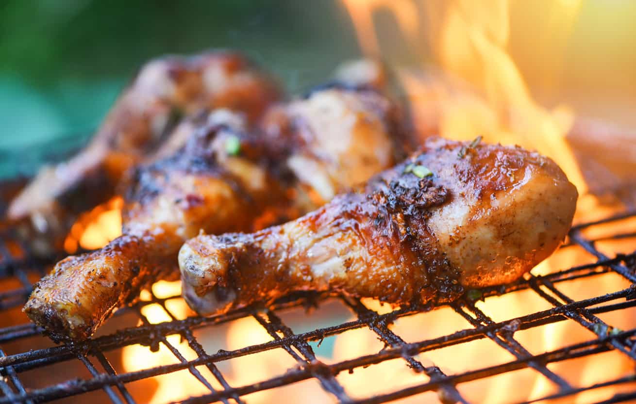 Grilled chicken legs barbecue with herbs and spices / Tasty chicken legs on the grill with fire flames marinated with ingredients cooking picnic outdoors