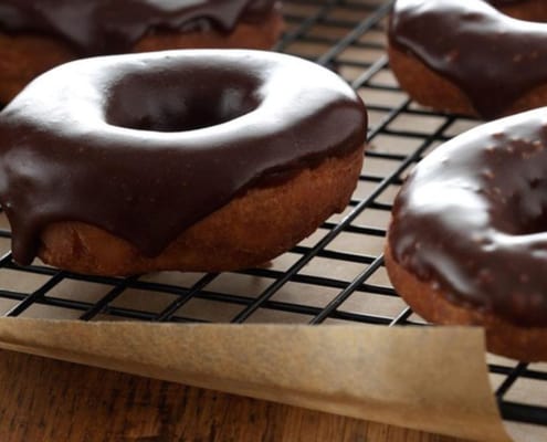 potato doughnuts with chocolate glaze cooling on a rack
