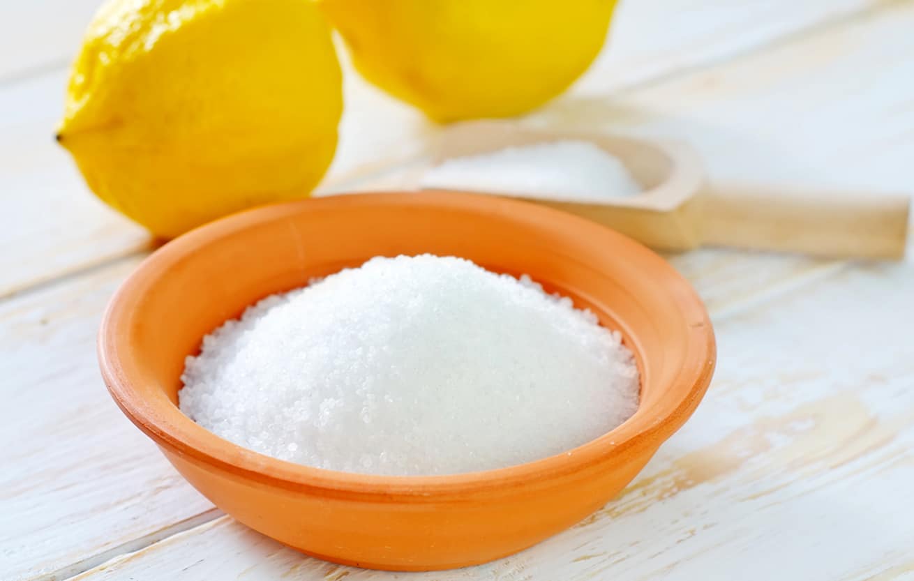 citric acid in a bowl with lemons in the background