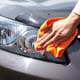 Hand with microfiber cloth cleaning car headlight covers.