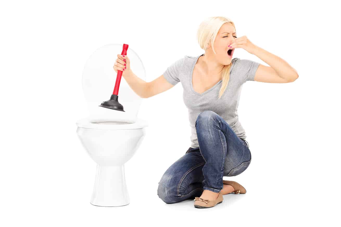 Woman unclogs a stinky toilet with plunger isolated on white 