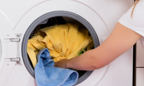 woman removing clothes and towels from clothes dryer