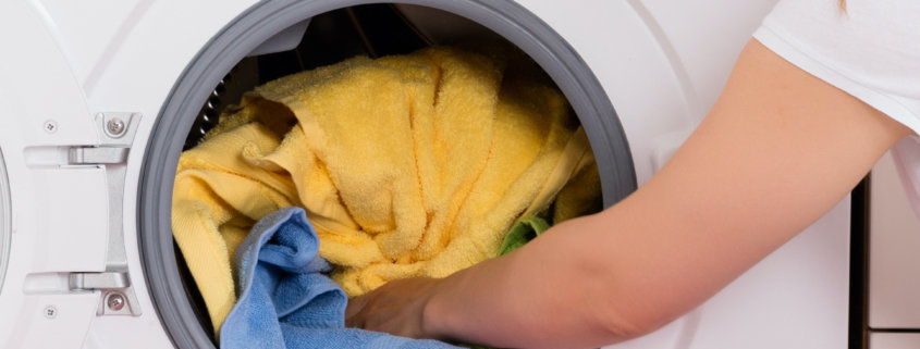 woman removing clothes and towels from clothes dryer