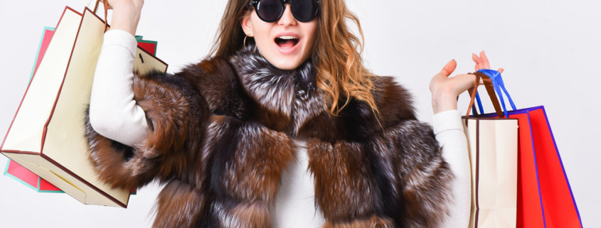 Woman shopping luxury boutique. Girl wear sunglasses and fur coat shopping white background. Lady hold shopping bags. Discount and sale. Buy with discount on black friday. Shopping with promo code.