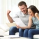 Excited couple seeing their tax refund status sitting on a sofa in the living room at home