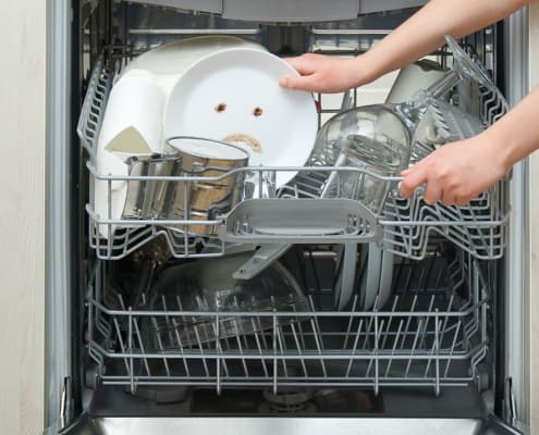 Poorly washed dishes in the dishwasher. Integrated Dishwasher with white plates front vew and sad emotion on plate. broken dishwasher machine concept