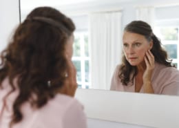 woman looking in mirror diagnosing herself with disease to please