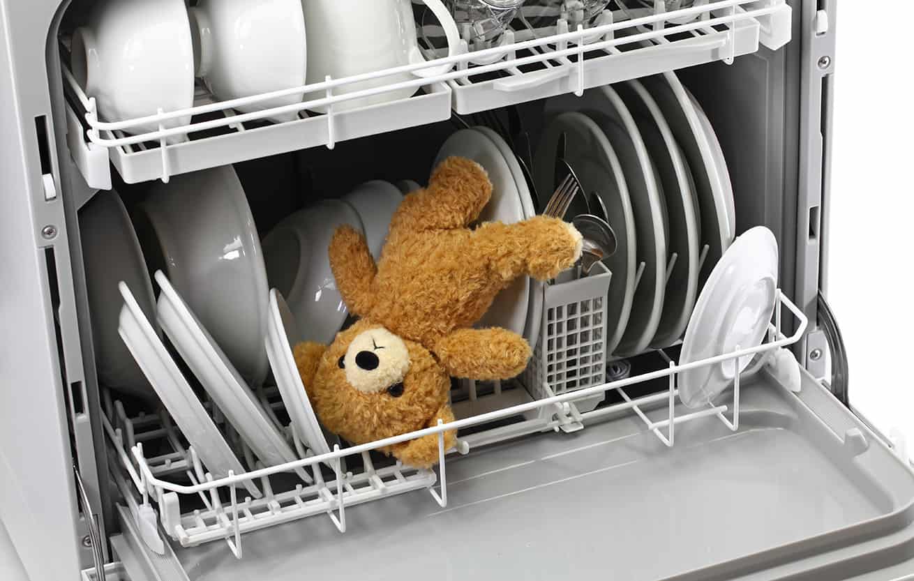 dishwasher holding toy bear with white dishes