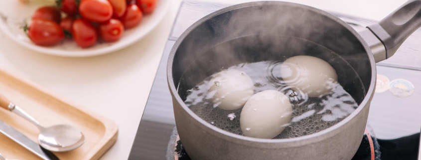 Three eggs boiling in pan of water