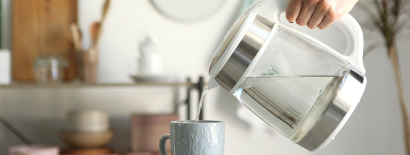 Pure water boils in an electric kettle on the table in the kitchen