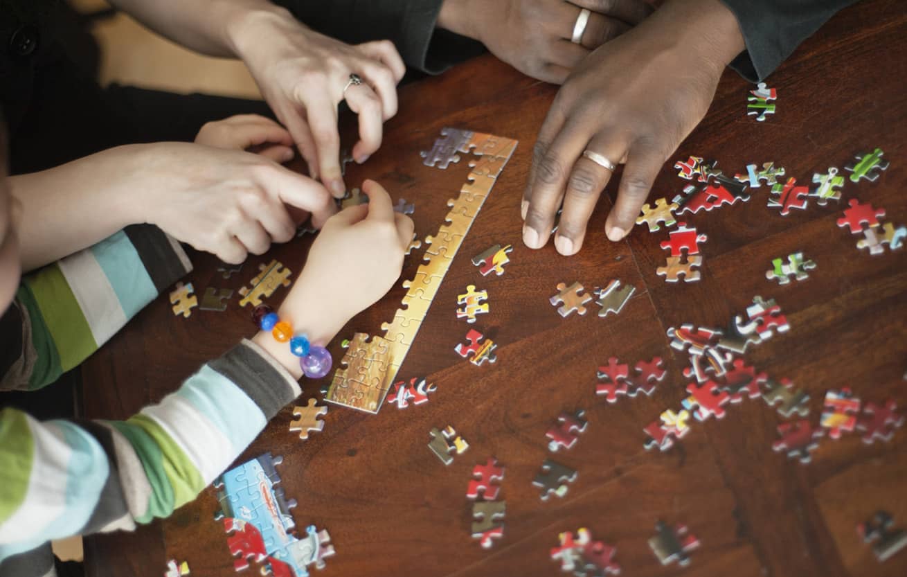 family solving jigsaw puzzle at table