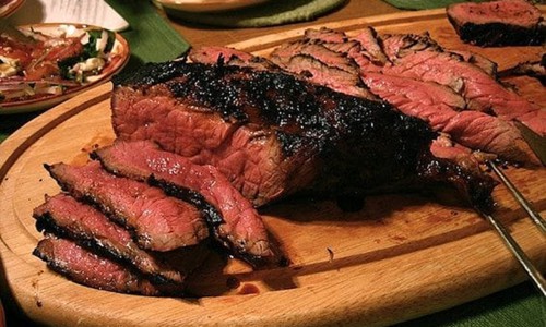 flank steak sliced on wood platter