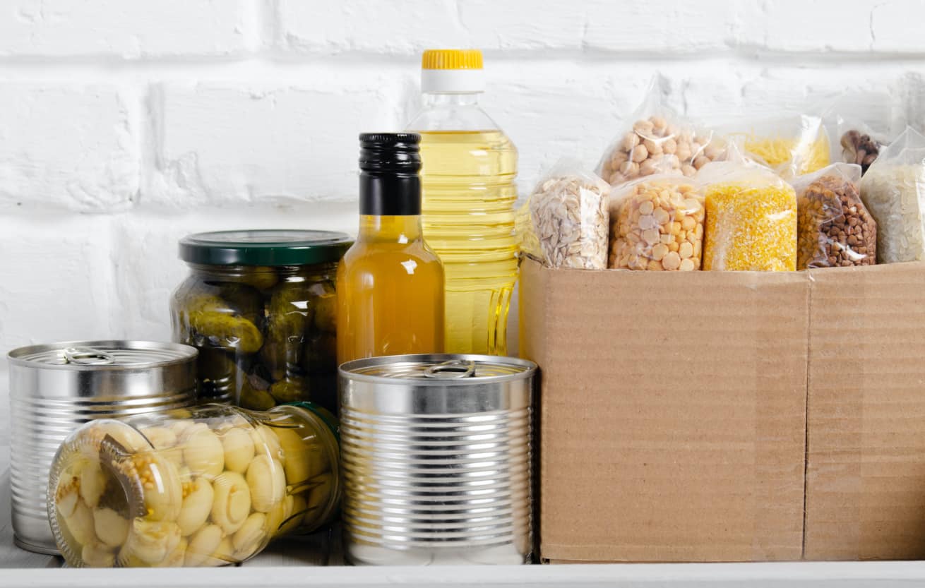 Set of uncooked foods on pantry shelf prepared for disaster emergency conditions on brick wall background closeup view