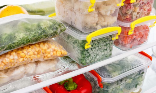 Frozen food in the refrigerator. Vegetables on the freezer shelves.