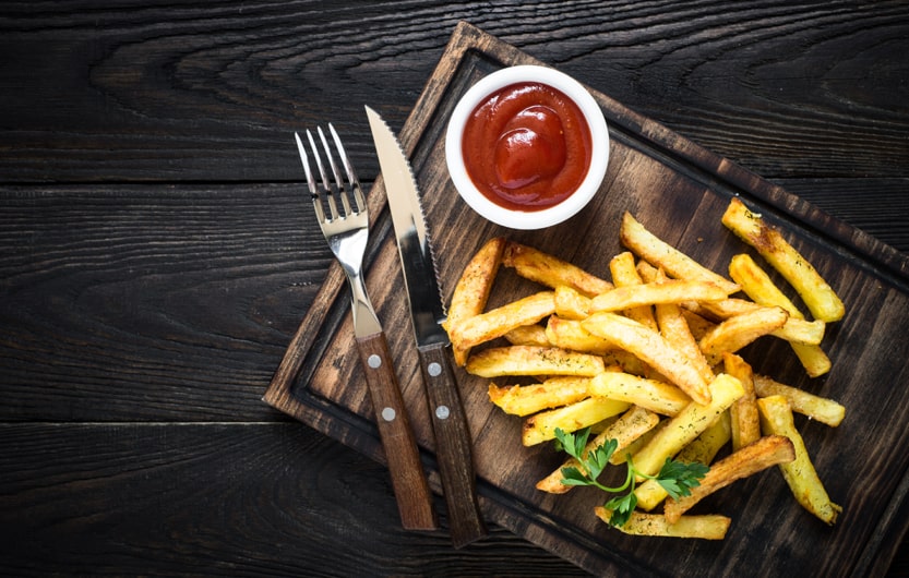 French fries with ketchup on wood tray