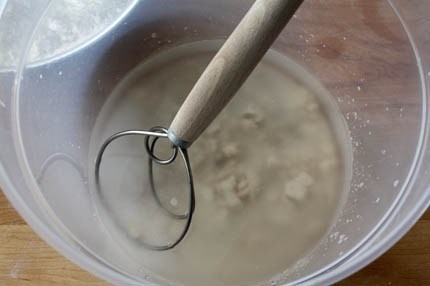 A bowl of soup and a spoon, with Bread and Dough