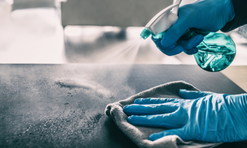 gloved hands spraying countertop