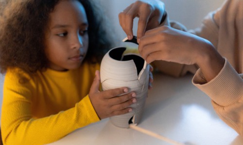 young girl getting help with gluing back together a broken white vase