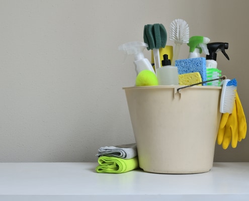 cleaning products in a bucket on white table