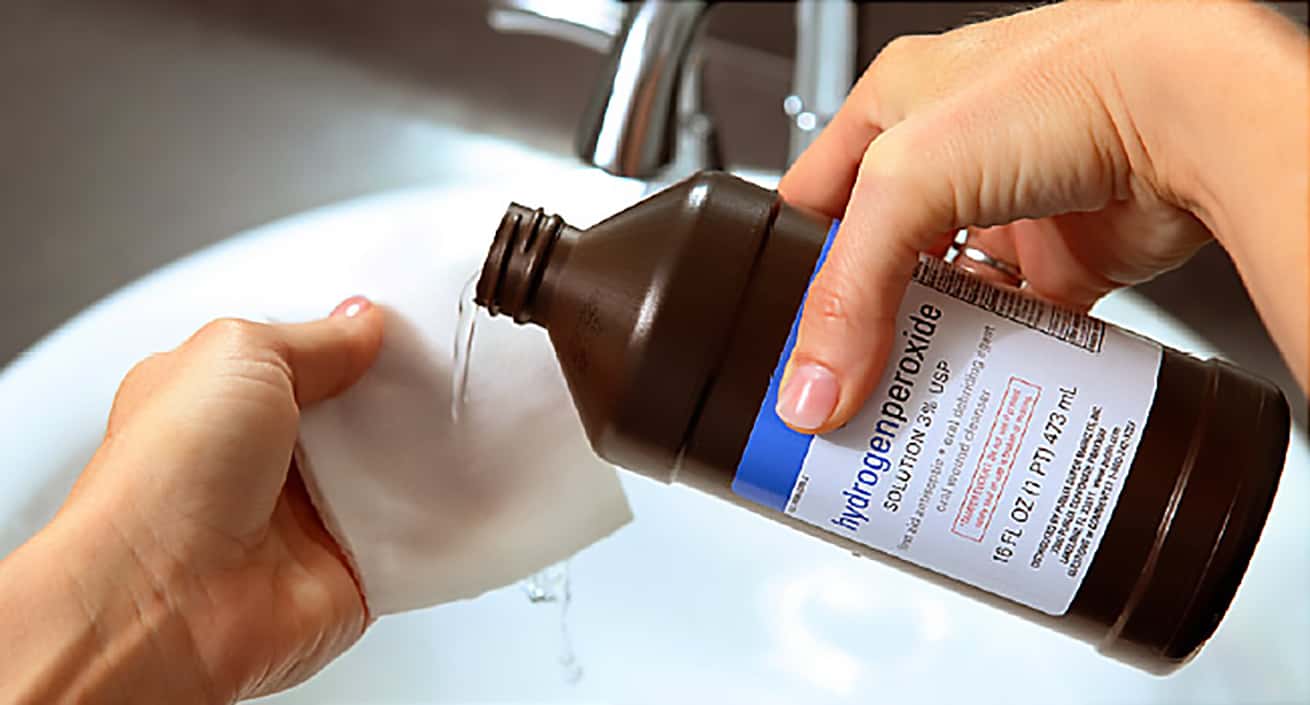 closeup of female hands pouring hydrogen peroxide into a clean cloth