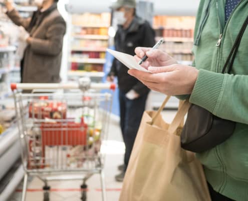Woman with a shopping list at a grocery store with people shopping in the background