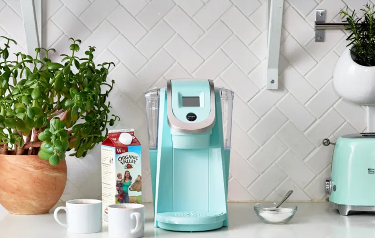 turquoise keurig coffee machine with cream sugar on white countertop