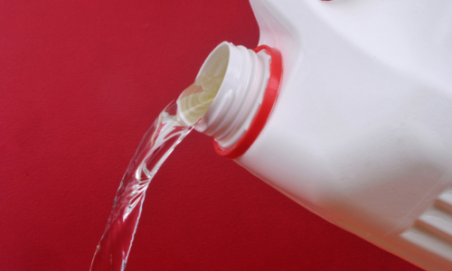 Pouring bleach close up on red background