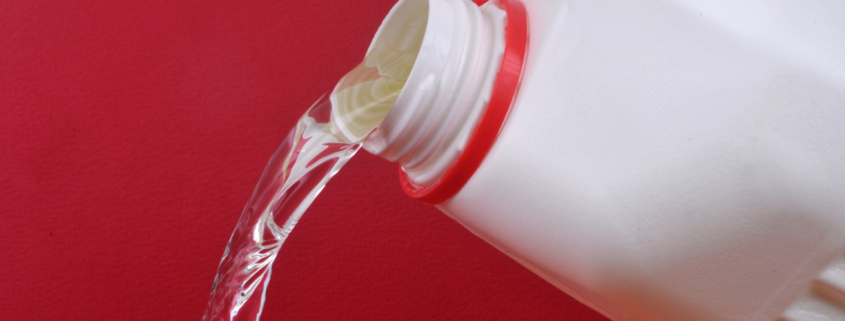 Pouring bleach close up on red background