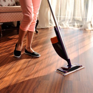 female cleaning laminate floor with modern spray mop