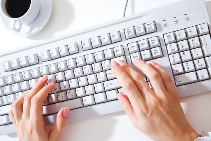 female hands typing on white computer keyboard on white desk