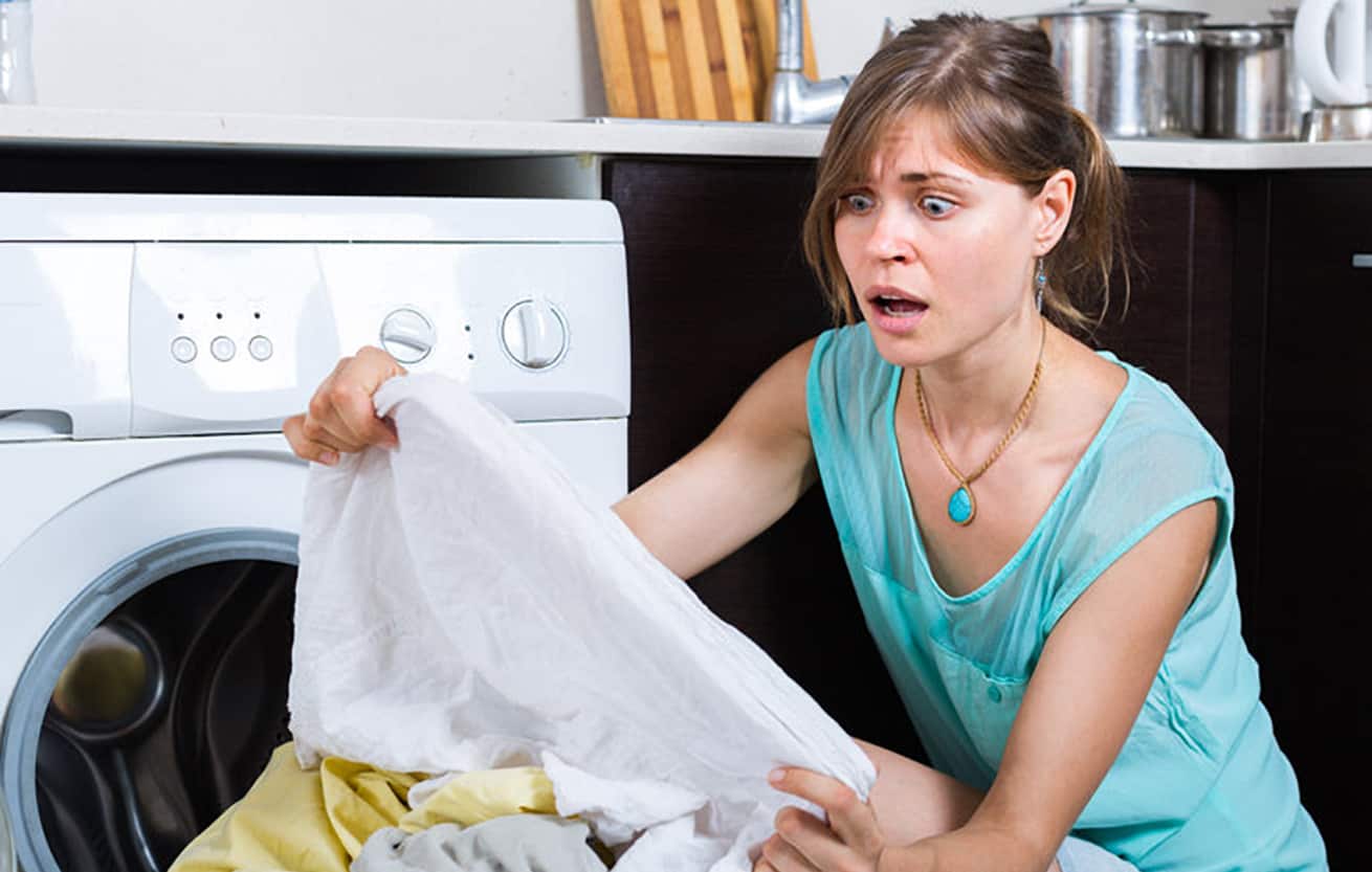 upset woman looking at laundry disaster