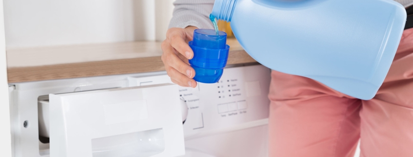 Close-up Of Female Hands Pouring homemade laundry detergent In The Blue Bottle Cap
