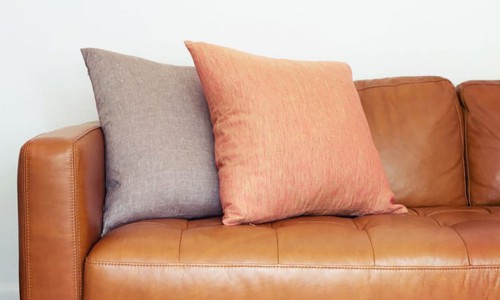 brown leather sofa with pillows of contrasting color