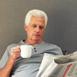 senior man reading newspaper drinking coffee