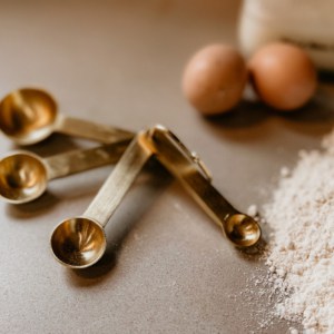 measuring spoon on counter with eggs and flour