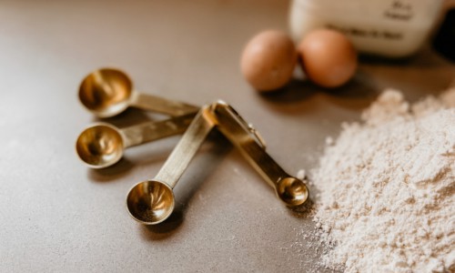 measuring spoon on counter with eggs and flour
