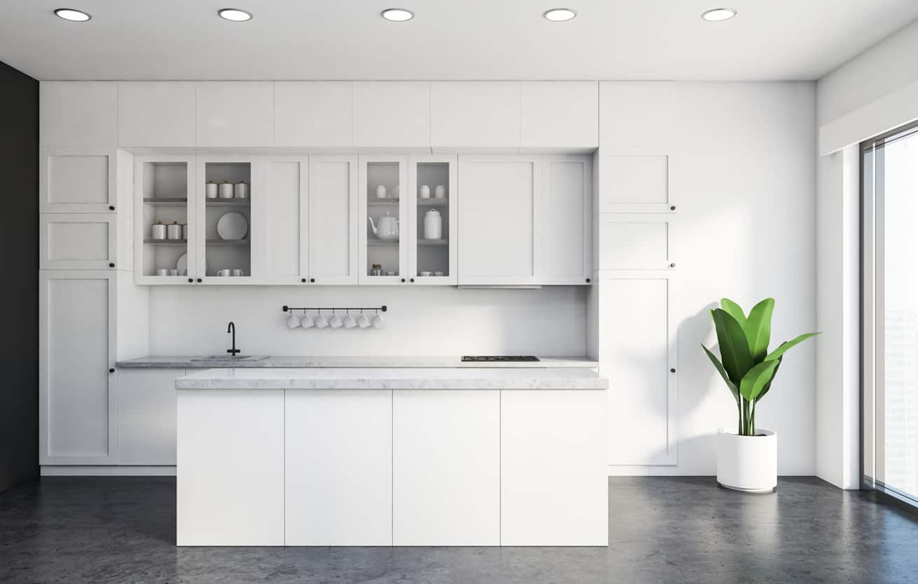 vInterior of classic kitchen with white and grey walls, concrete floor, white countertops and cupboards and comfortable white island