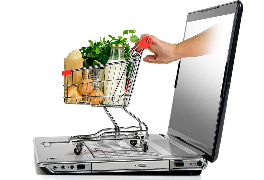 Hand pushing a small shopping cart from laptop screen isolated in white