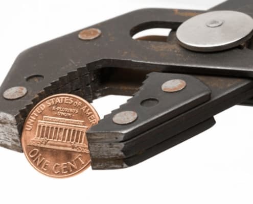 penny pinching concept with penny held in vice grips