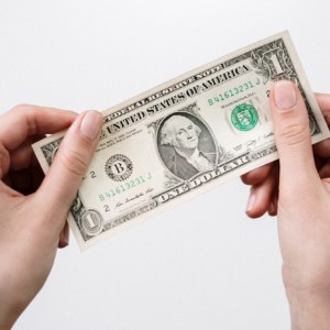 female hands holding a one-dollar bill