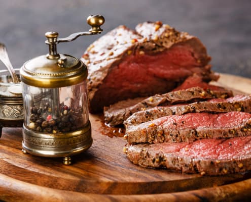 Roast beef on cutting board with saltcellar and pepper mill