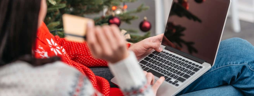 cropped shot of young couple shopping online with credit card and laptop at christmas