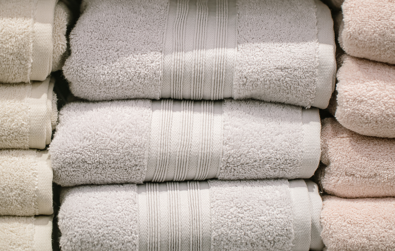a stack of luxury bath towels in 3 colors on a shelf
