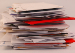 A pile of colorful letters and junk mail on a table isolated on greyish background