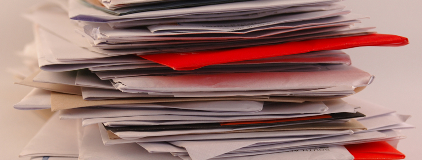 A pile of colorful letters and junk mail on a table isolated on greyish background