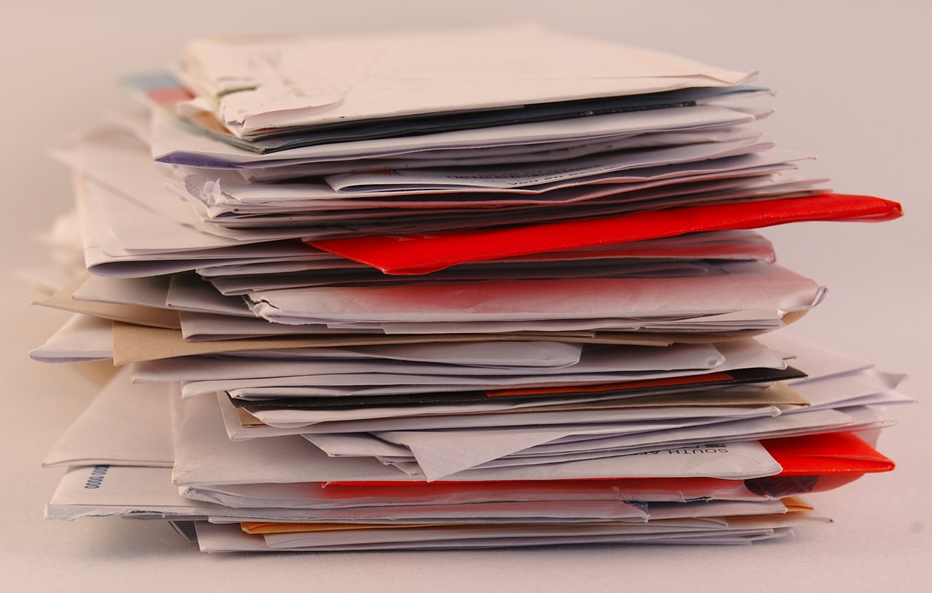 A pile of colorful letters and junk mail on a table isolated on greyish background