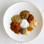 A plate of piles of various spices used in making a taco seasoning blend.